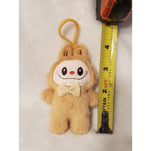 Tan Labubu stuffed keychain and bag charm featuring a stylish bow tie.